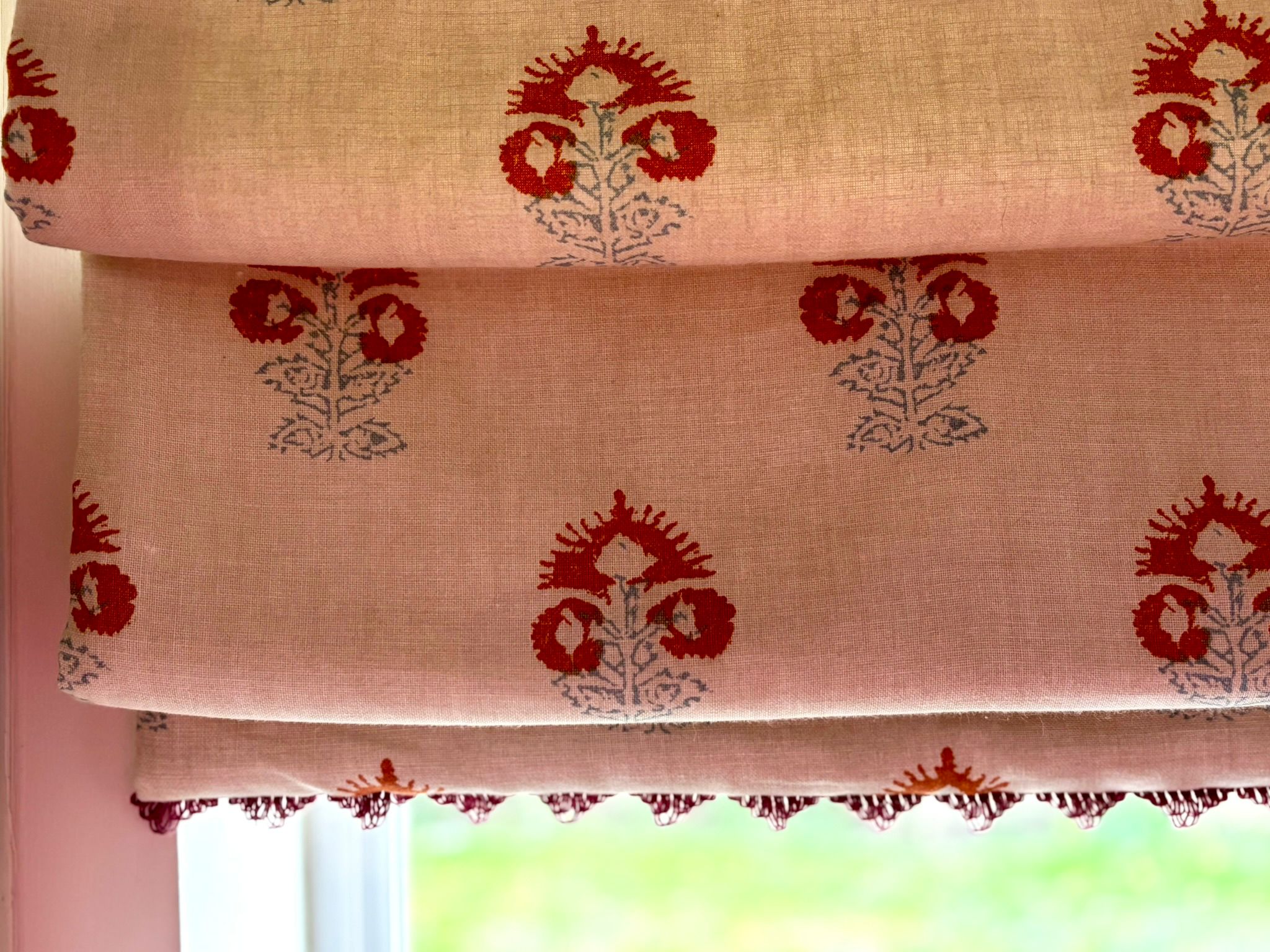 Pink and red block-print Roman blind in linen with hand-finished pom-pom trim